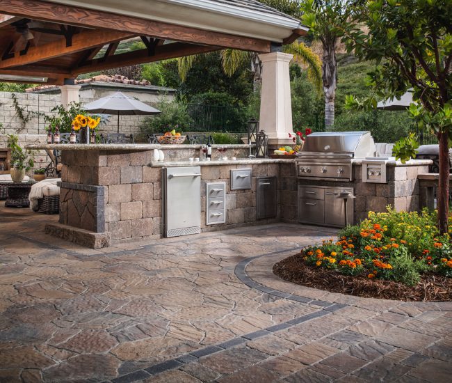 An elegantly designed and installed hardscape paver stone outdoor kitchen that enhances the outdoor cooking experience