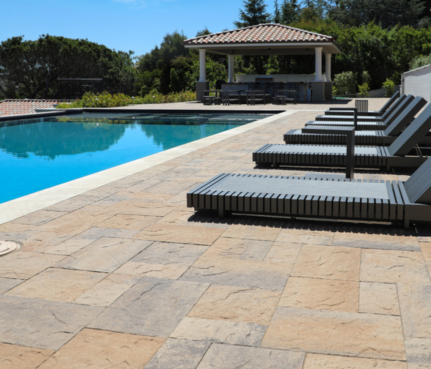 A beautiful custom swimming pool, surrounded by a paver stone pool deck